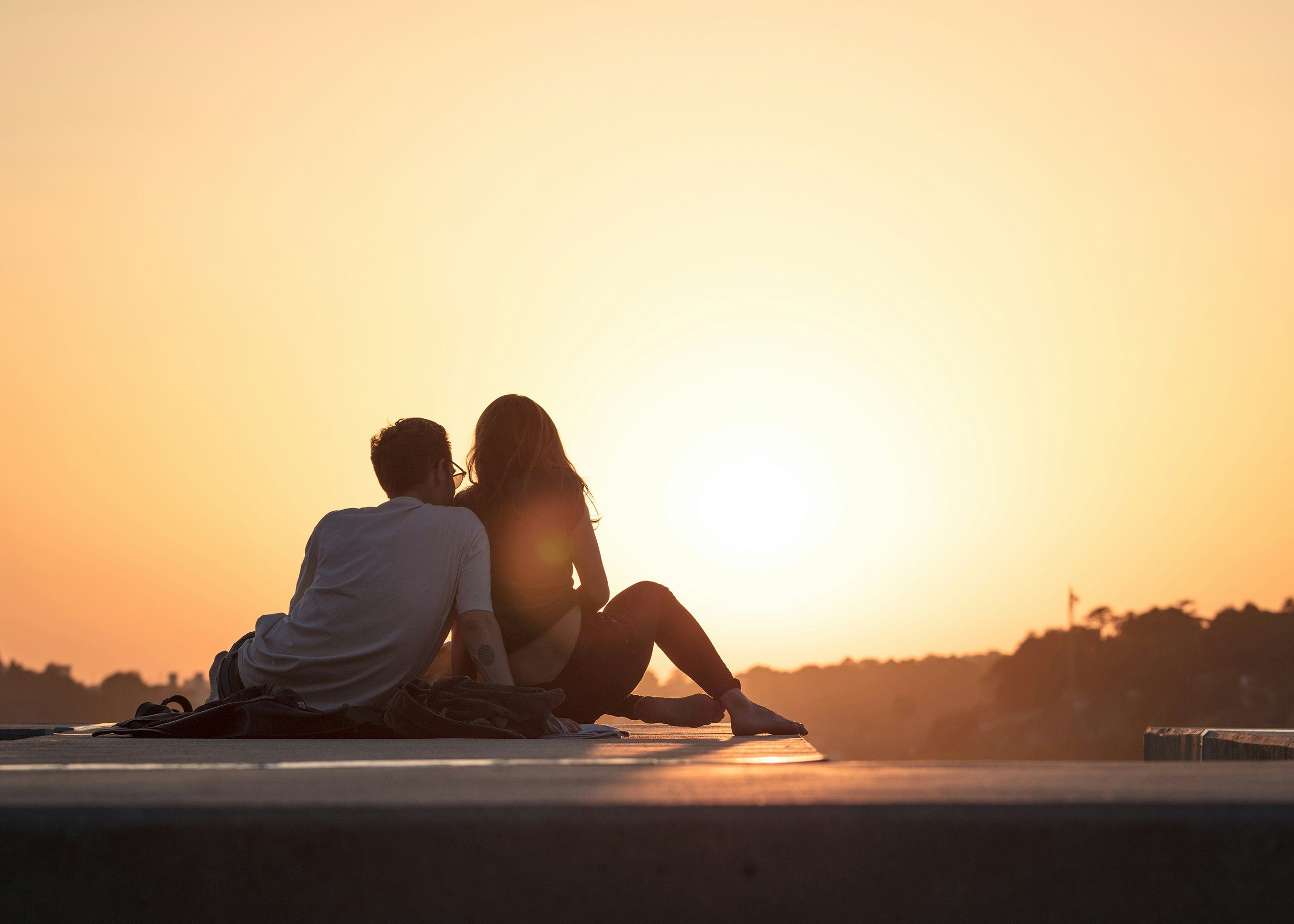 A couple sitting together watching the sun set over the water