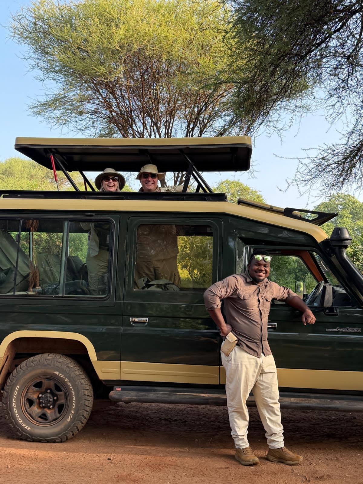 A safari guide standing beside an open safari vehicle