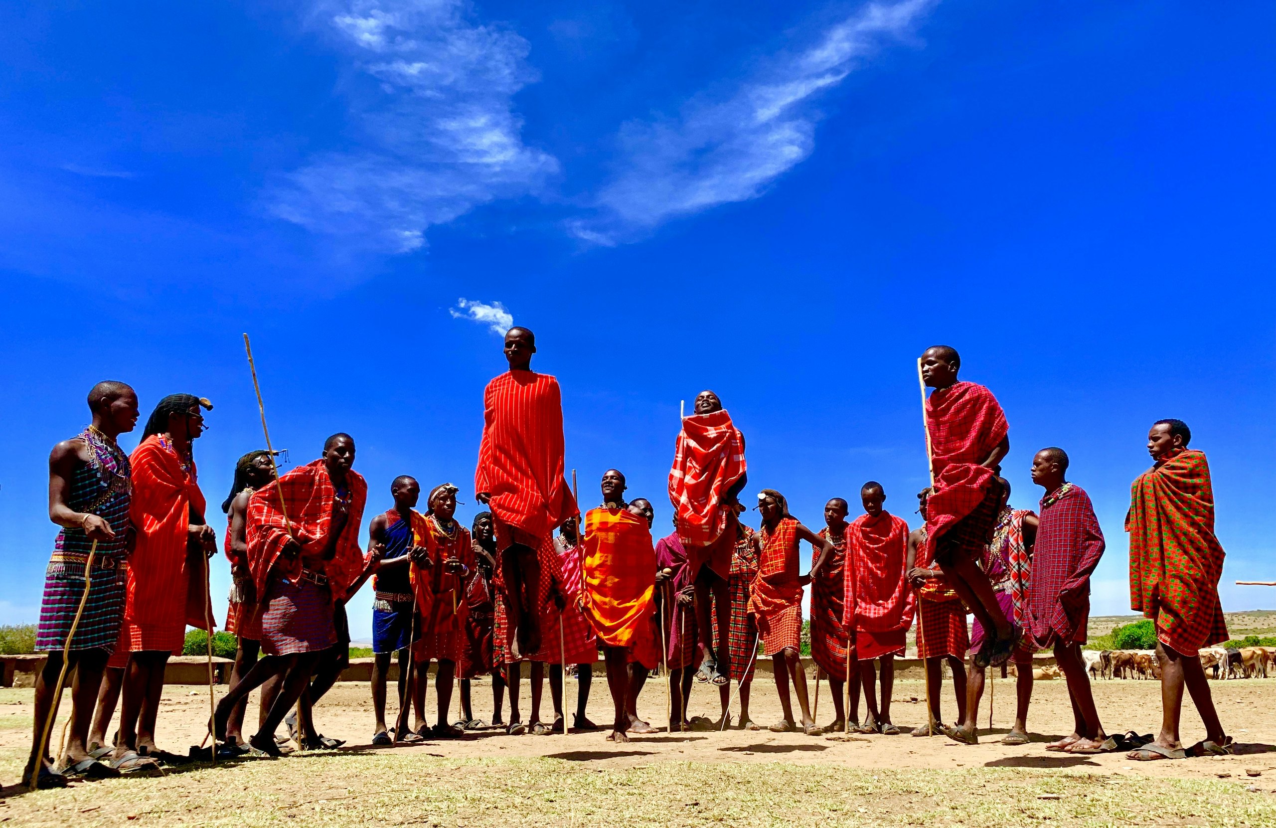 Maasai warriors performing a jumping dance under a blue sky